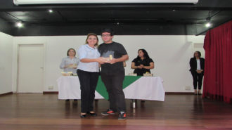 Foto de um usuário com certificado na mão, ao lado da técnica Fabiana.