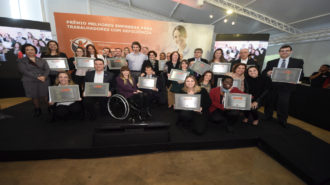 Foto conjunta com todos os representantes das empresas premiadas com suas respectivas placas e ao fundo o painel do V Prêmio Melhores Empresas para Trabalhadores com Deficiência.