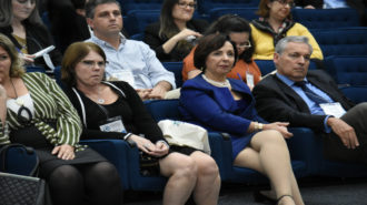 Foto da Dra. Linamara Rizzo Battistella (Secretária de Estado dos Direitos da Pessoa com Deficiência de São Paulo) sentada ao lado de outros convidados no auditório.