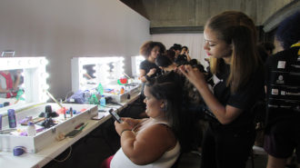 Foto de modelo arrumando o cabelo no camarim do evento.