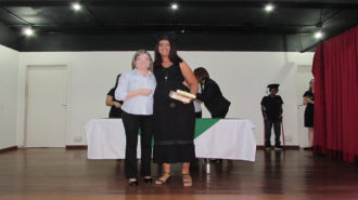 Foto de uma usuária com certificado na mão, ao lado da técnica Cristina.