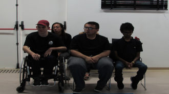 Foto de cinco adolescentes do curso Laboratório de Imagem sentados em cadeiras pretas.