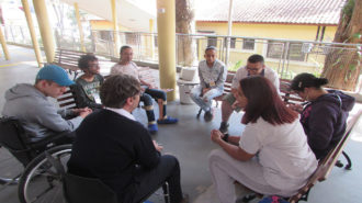 Foto do pátio do Centro de Tecnologia e Inovação. Sete usuários e um técnico estão sentados e conversando.