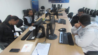 Foto de quatro usuários sentados em frente aos computadores.