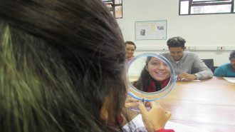 Foto de uma usuária segurando um espelho e sorrindo.
