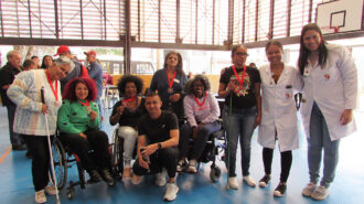 Imagem colorida da quadra do SRLMH. Pessoas com e sem deficiência posam para a foto. Ambas utilizam uma medalha.