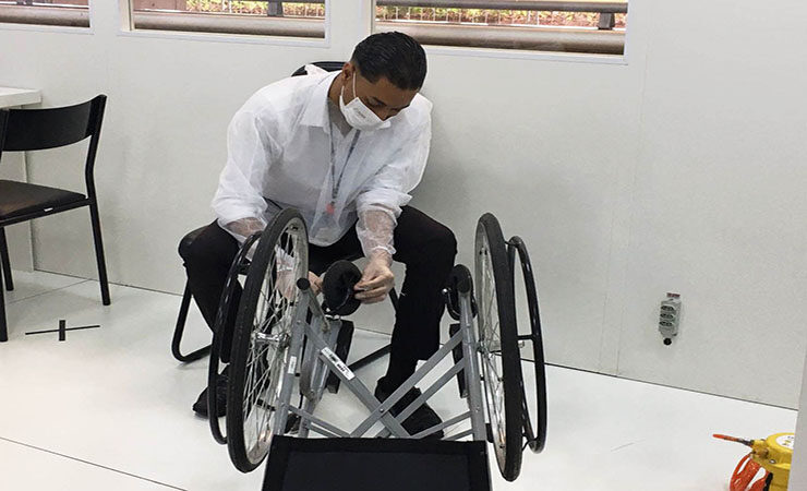 Imagem colorida do Centro de Informação à Pessoa com Deficiência - Barra Funda. Técnico realizando manutenção em uma cadeira de rodas.